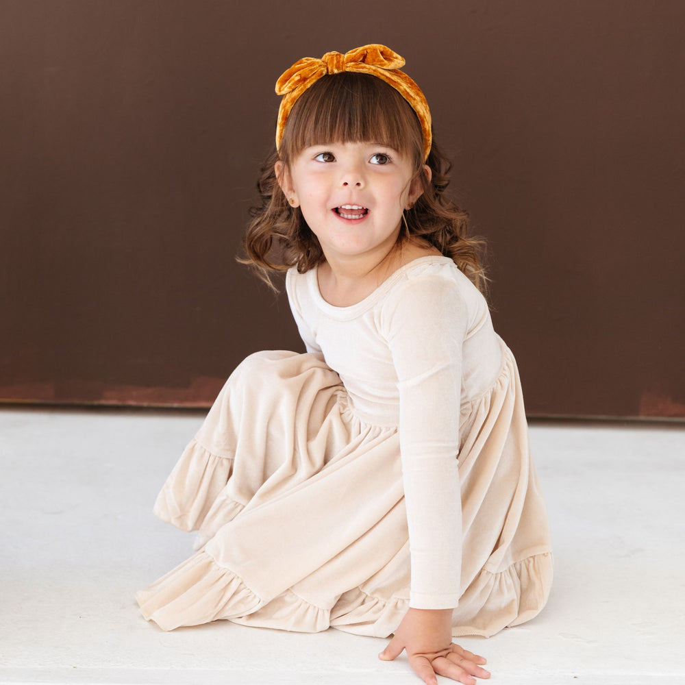 little girl in long sleeve cream velvet twirl dress and mustard velvet headband for Thanksgiving