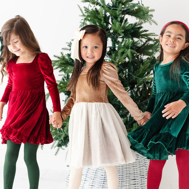 little girls in front of christmas tree wearing fancy christmas party dresses and tights