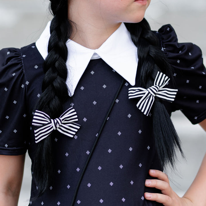 little girl dressed as wednesday for halloween with matching pigtail bows