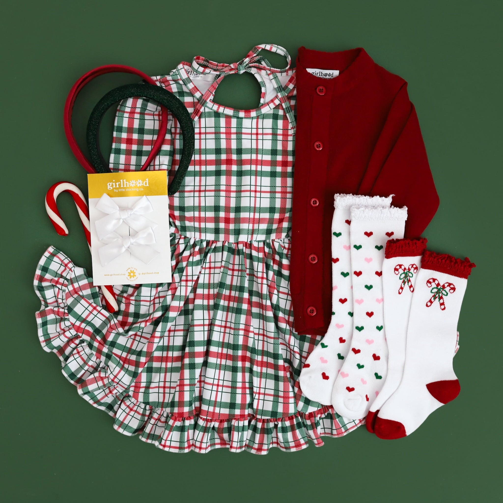 girls christmas outfit flatlay with plaid dress and cardigan and matching knee highs and bows