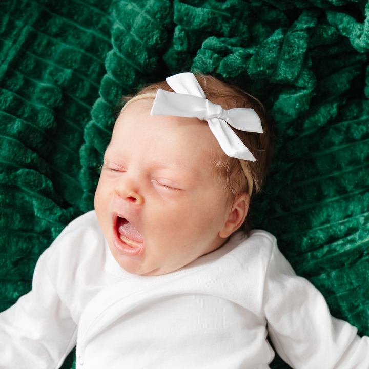 baby girl in white satin bow on soft nylon headband