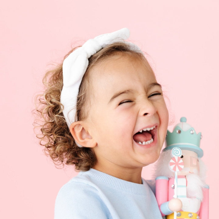 little girl in white velvet headband holding pastel nutcracker