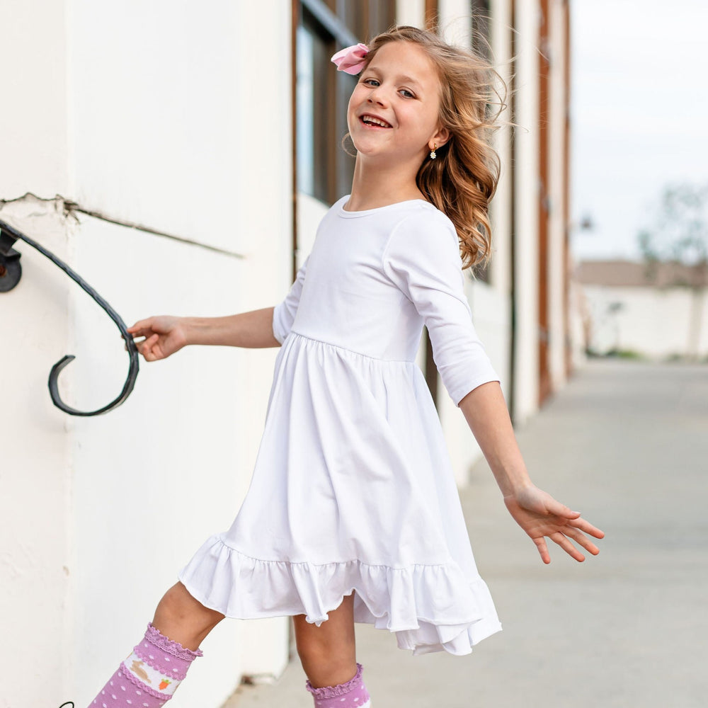 young girl wearing long sleeve white cotton twirl dress and purple easter bunny knee high socks
