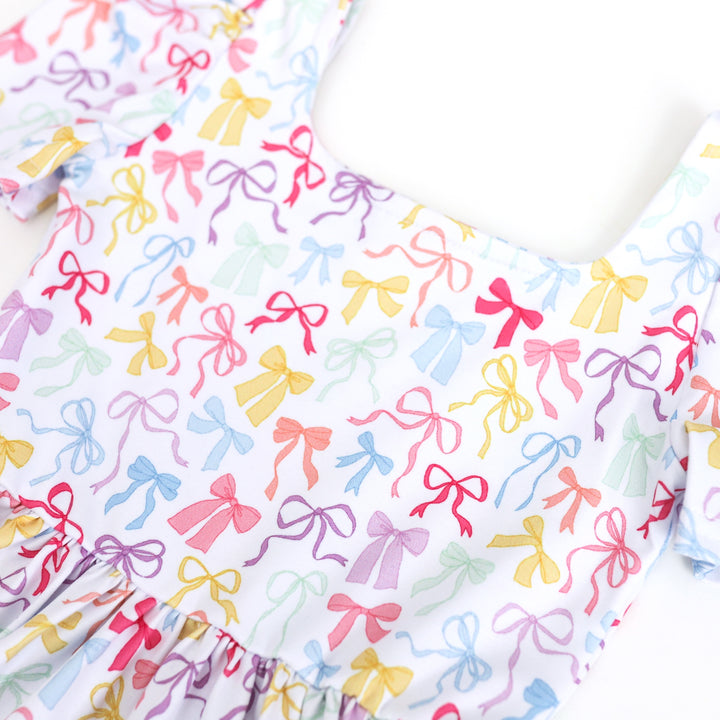 closeup of girl's white square neck dress with pastel bow print