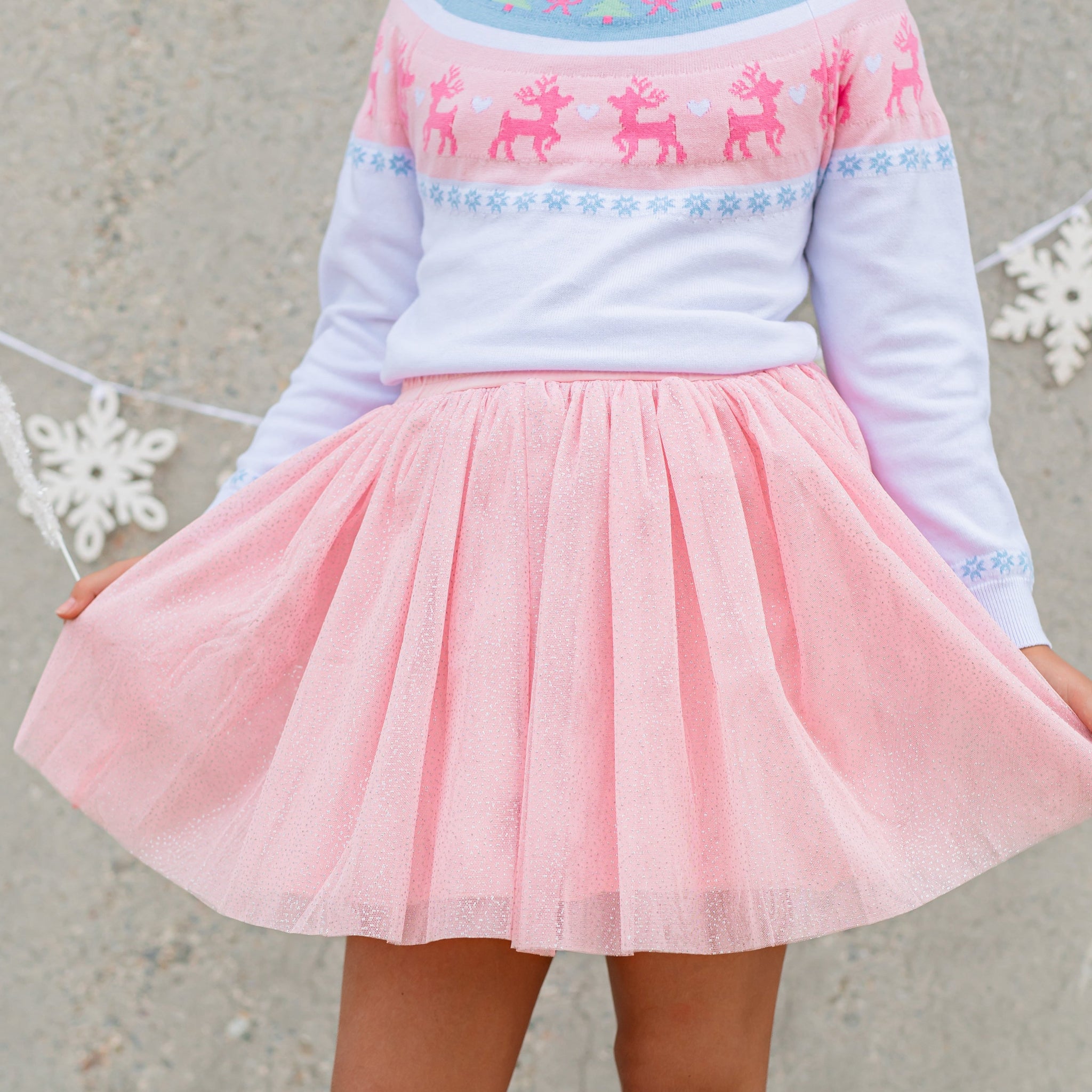 girl in cozy white knit sweater with pink and blue fair isle reindeer print paired with sparkly light pink tutu skirt with tiny silver sparkles