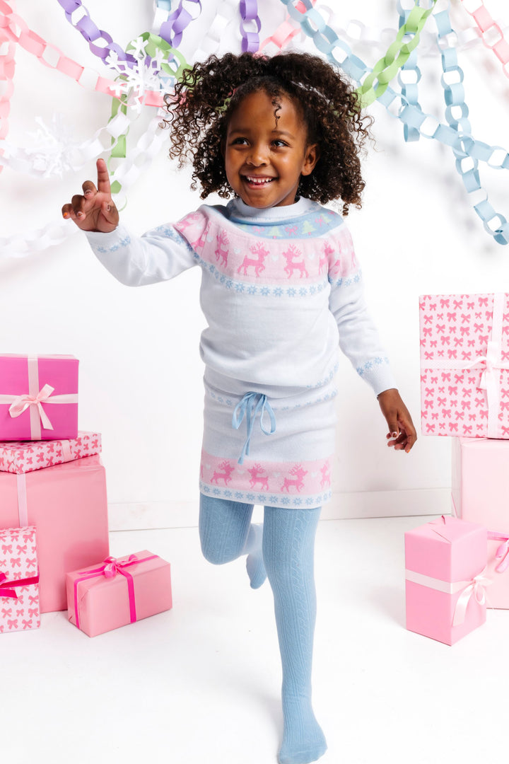 little girl in winter white pullover sweater and matching sweater skirt with pastel fair isle print and blue cable knit tights