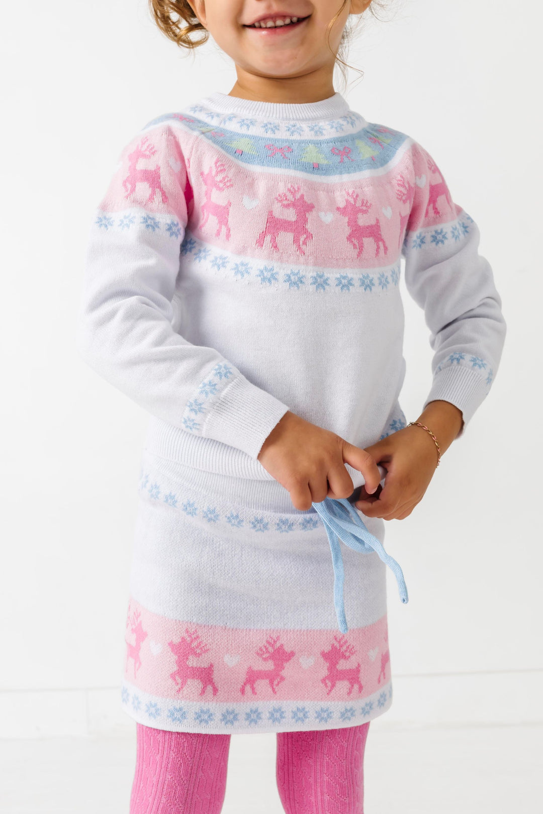 girl in white pullover sweater and sweater skirt with pastel fair isle design paired with pink cable knit tights for winter winderland
