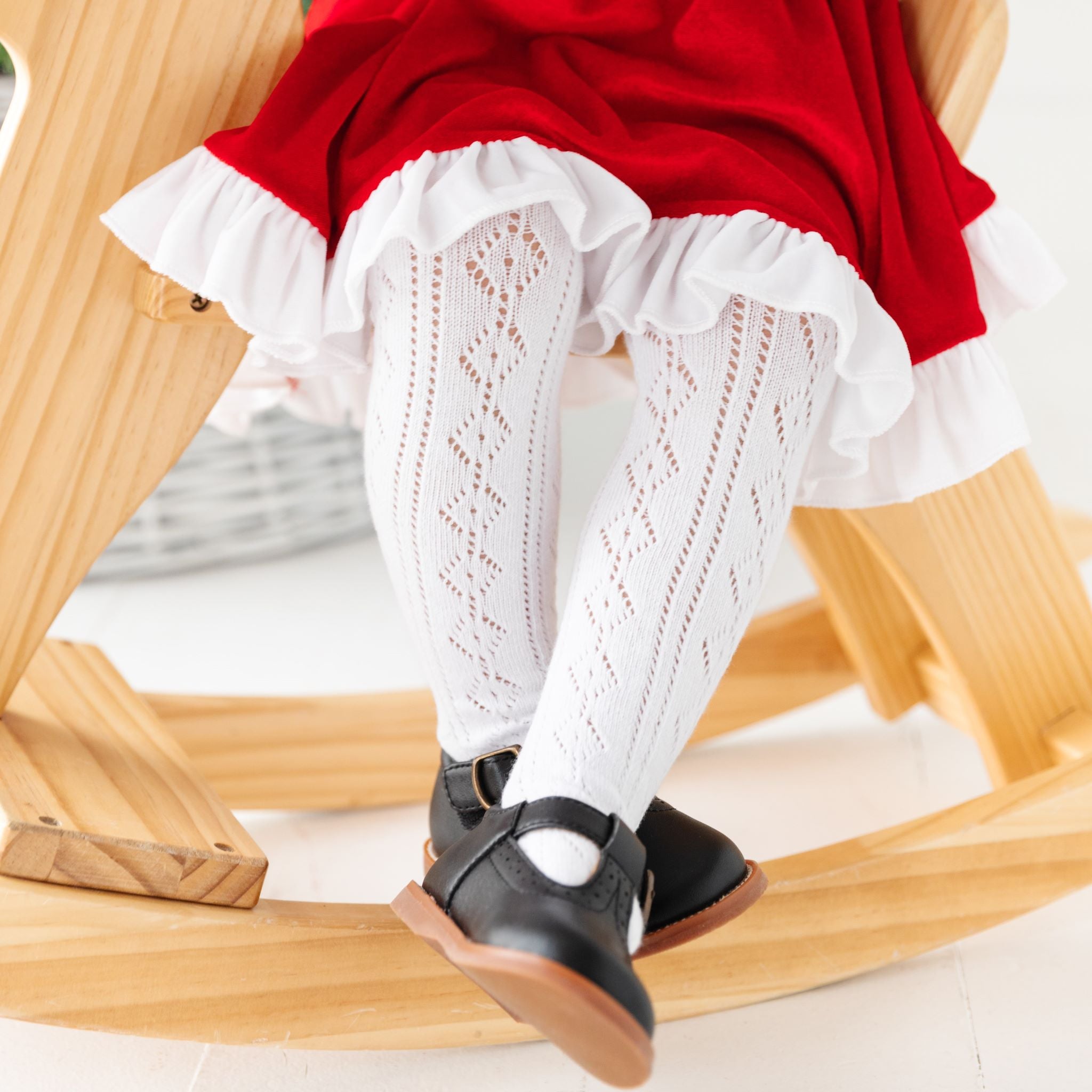 Closeup of little girl in open knit white tights with velvet Santa dress