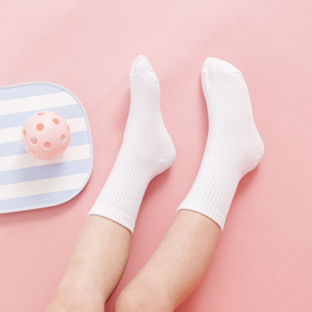 little girl in white crew socks beside pickleball paddle