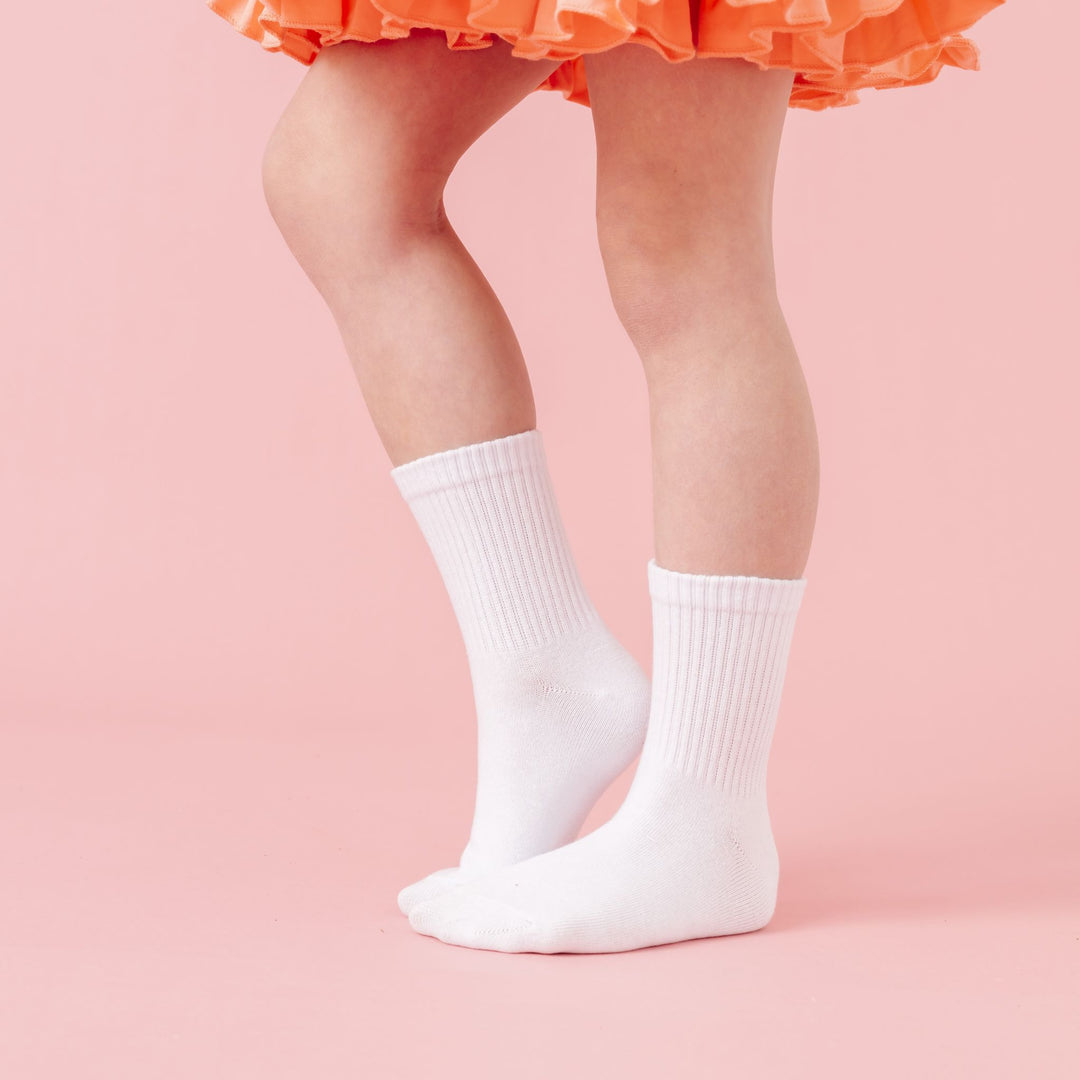 little girl in orange summer twirl dress and white crew socks 