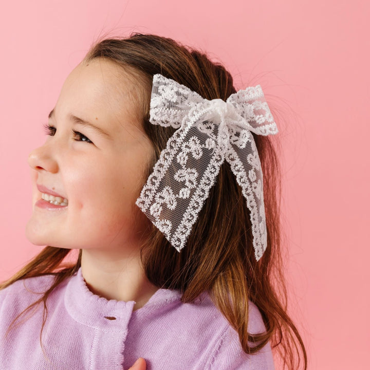 young girl in white lace hand tied hair bow on clip and lavender cardigan for spring and valentines day