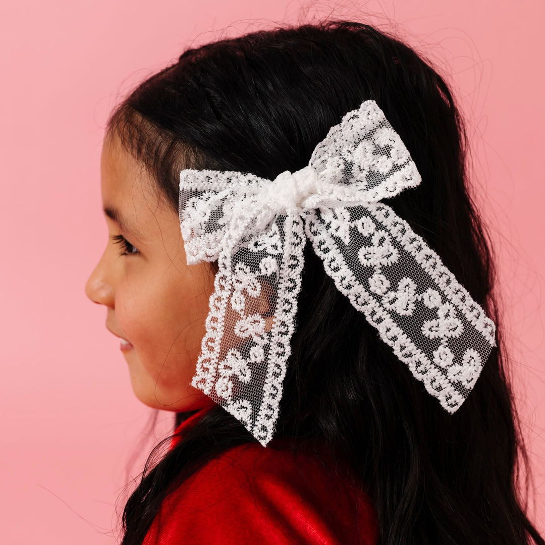 little girl in red velvet outfit paired with white lace bow on alligator clip for valentines day vibes