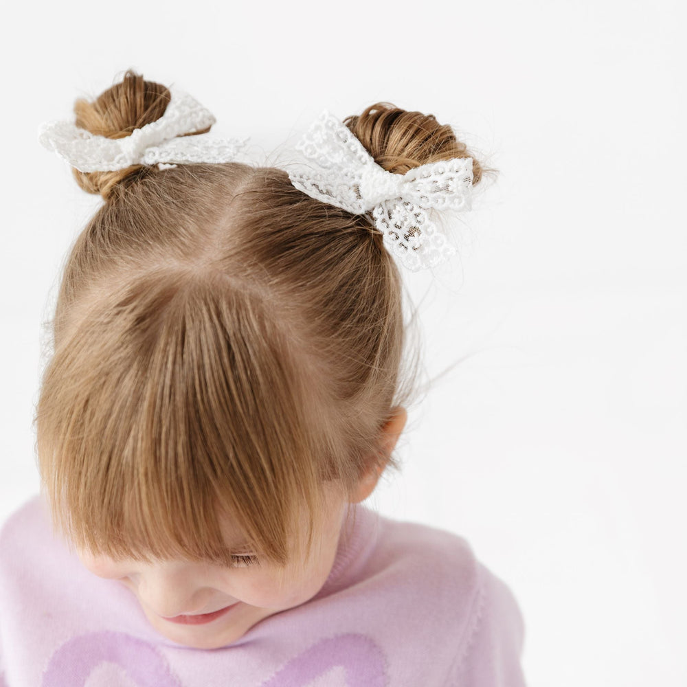 little girl in white lace pigtail bows on clips paired with lavender bow sweater for spring