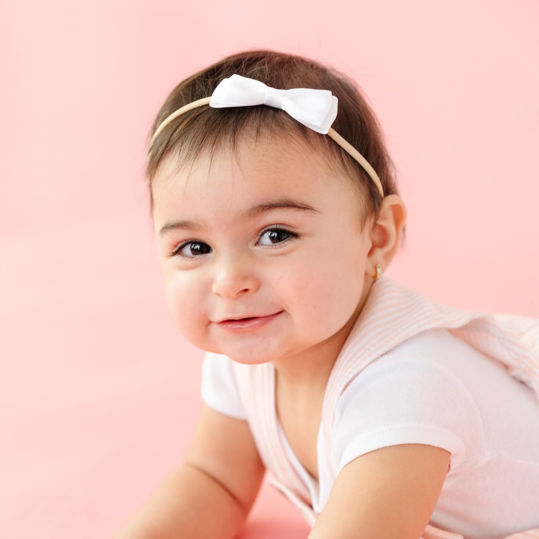 baby girl in white satin ribbon bow on stretchy nylon headband