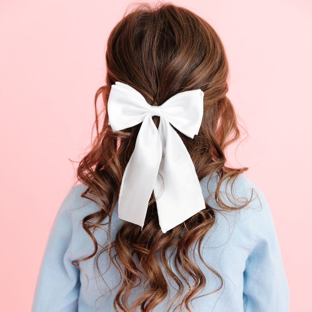 young girl with hair pulled back in winter white satin oversized ribbon hair bow on clip