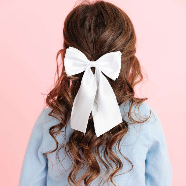 girl in white satin winter occasion bow and pastel blue sweater