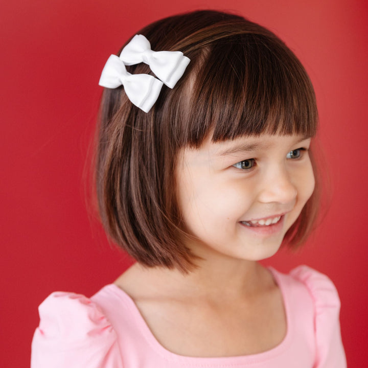 little girl in white satin pigtail bows and light pink twirl dress for Valentine's Day