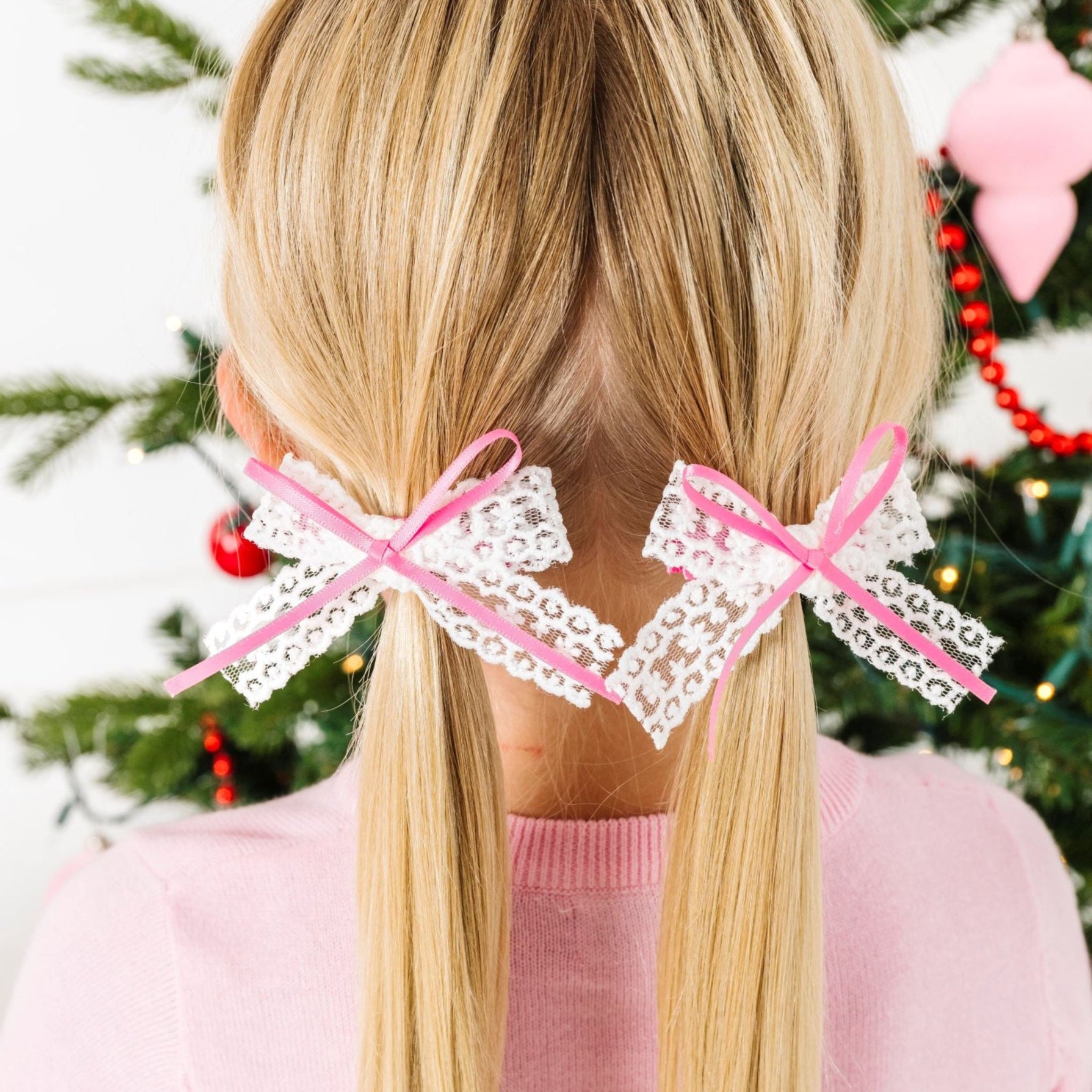 little girl in front of Christmas tree in white lace pigtail bows with pink satin ribbon