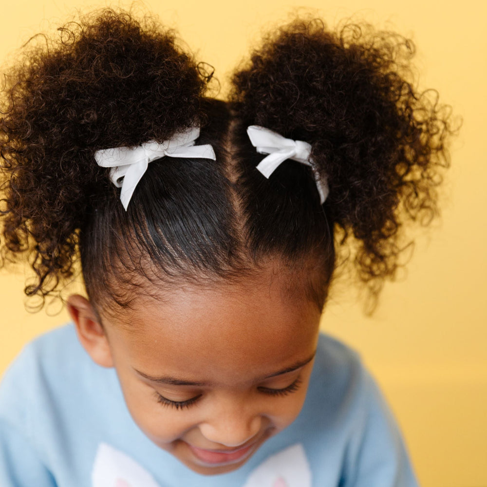 little girl in white velvet ribbon pigtail bows on clips to match easter sweater set