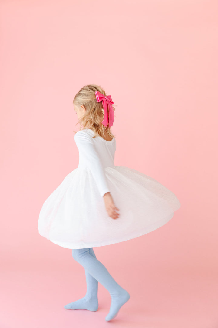 little girl twirling in velvet tutu holiday dress with pink satin bow and winter blue tights