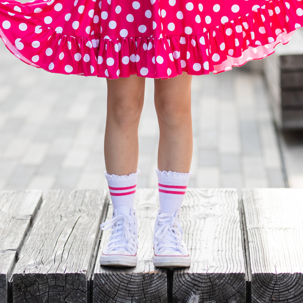 little girl wearing hot pink and white polka dot dress with amtching white and hot pink striped midi socks