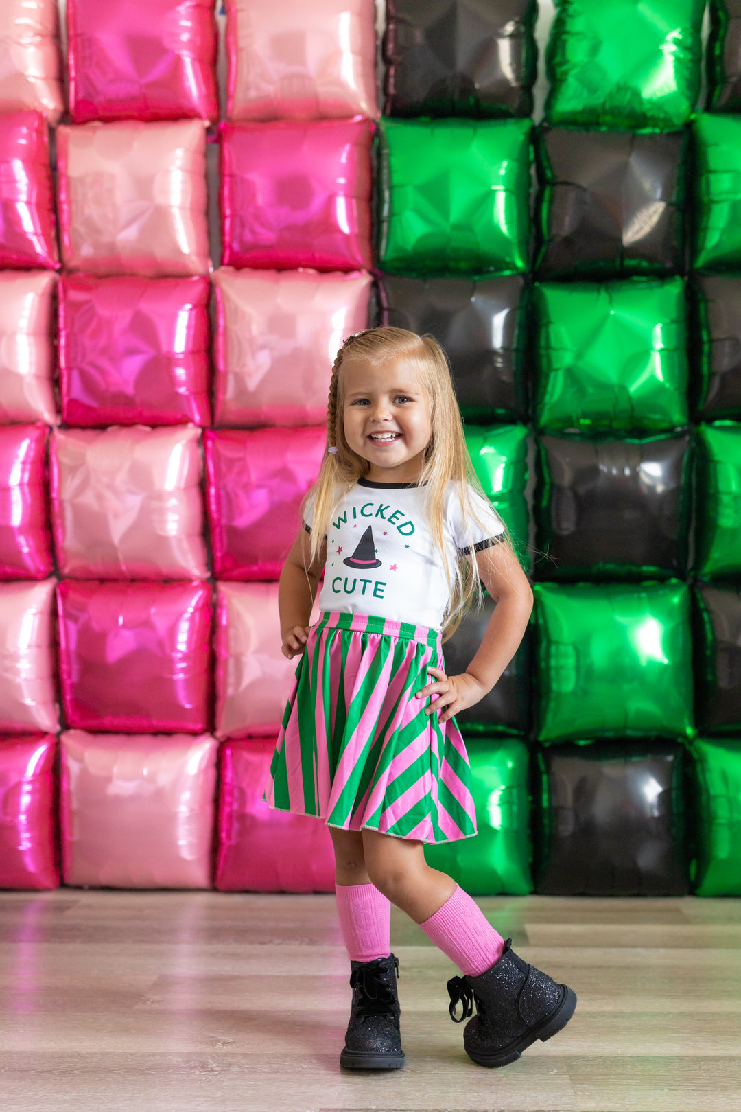 little girl in Wicked inspired top with witch hat design and matching pink and green striped skort