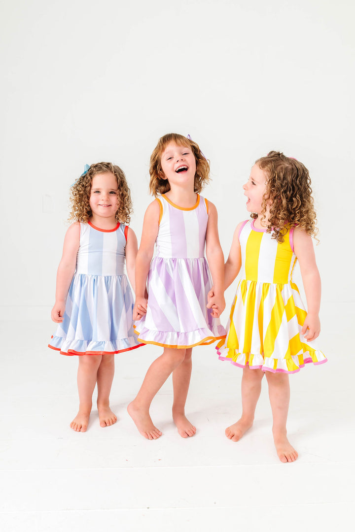 three girls in coordinating colorful wide striped summer twirl dresses with contrast binding
