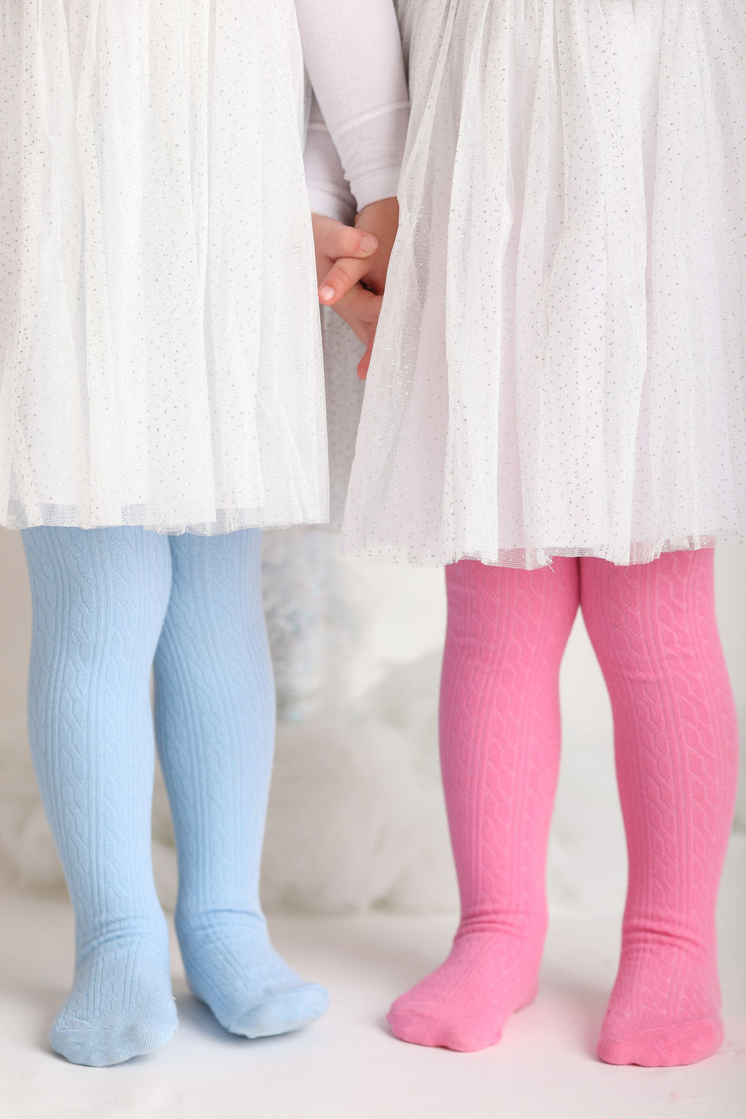 little girls in blue and pink cable knit tights with sparkly white tulle party dresses