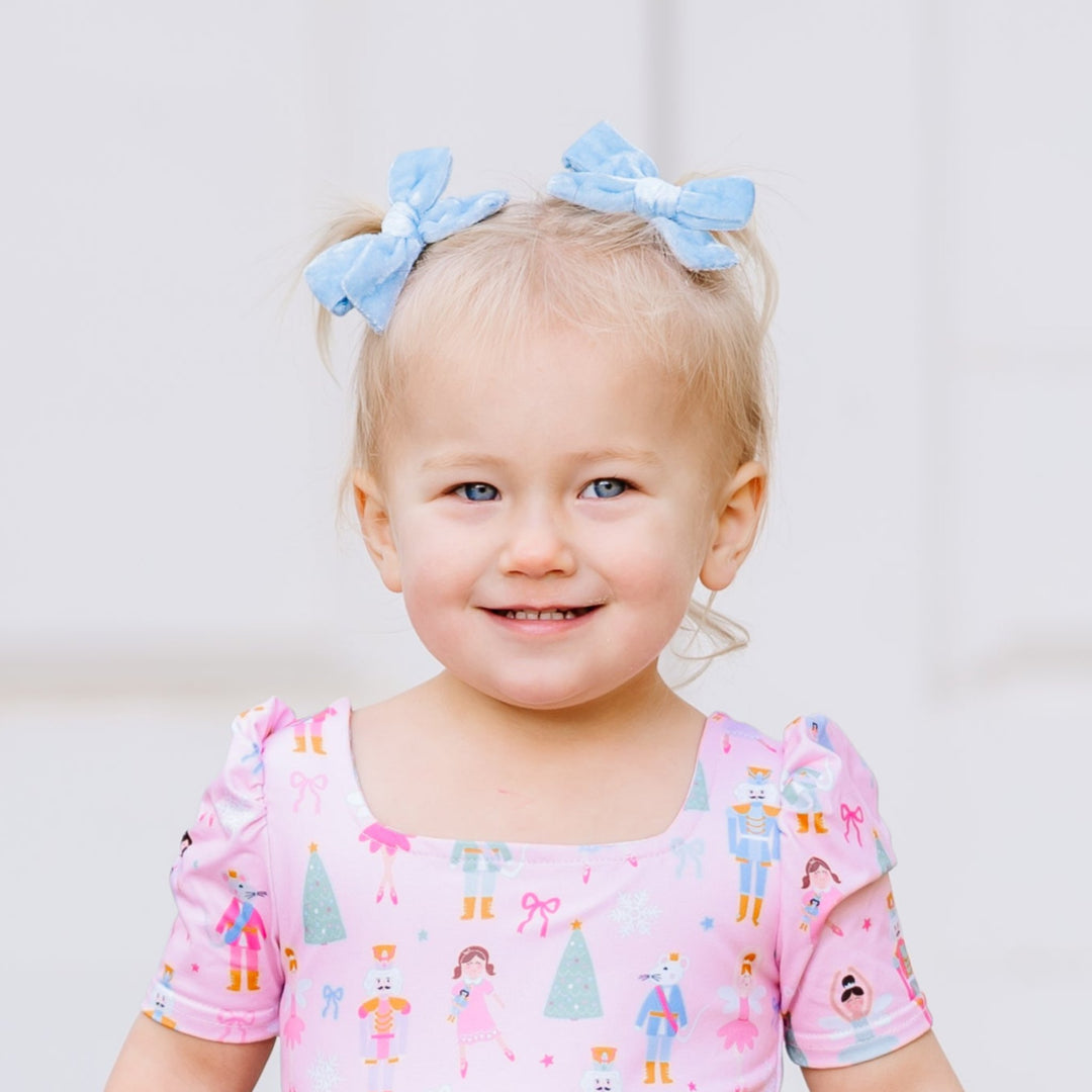 little girl in light blue velvet pigtail bows for Nutcracker themed Christmas outfit