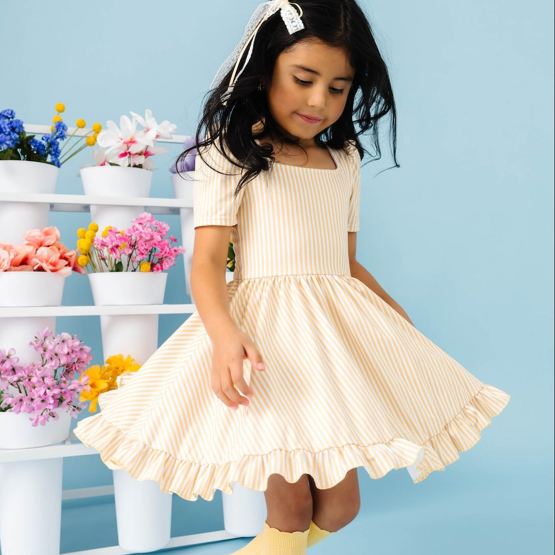 girl twirling in butter yellow stripe dress