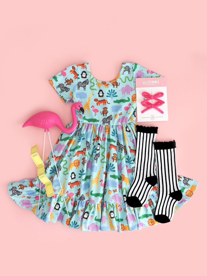 flatlay of girls' short sleeve, ruffle hem twirl dress in mint with colorful zoo animal print and matching knee highs and bows