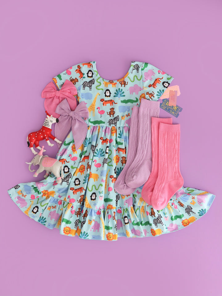 flatlay of girls' short sleeve, ruffle hem twirl dress in mint with colorful zoo animal print and matching pink and purple knee highs and bows