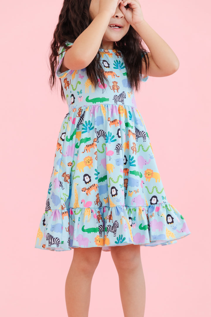 girl wearing short sleeve, ruffle hem twirl dress in mint with colorful zoo animal print