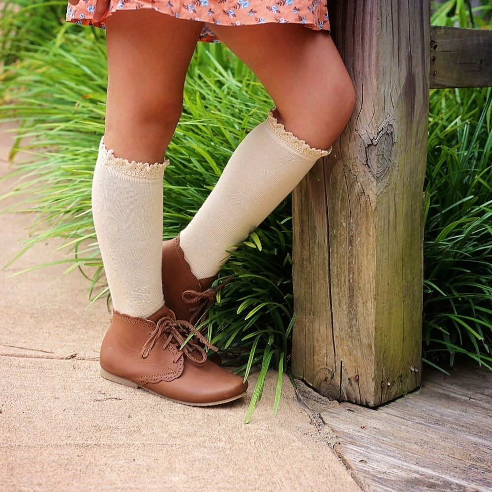 little girl in vanilla cream lace top knee high socks and brown leather shoes