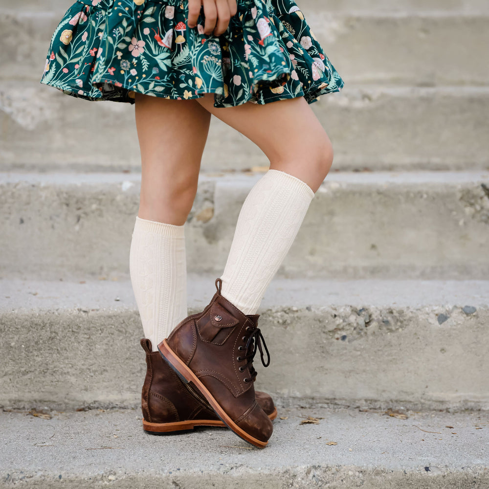 vanilla cream cable knit knee high socks paired with brown leather boots