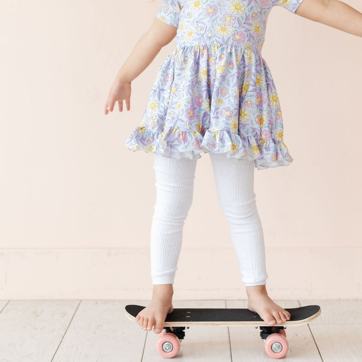 little girl on skateboard in white cable knit leggings and adorable spring pastel twirl dress