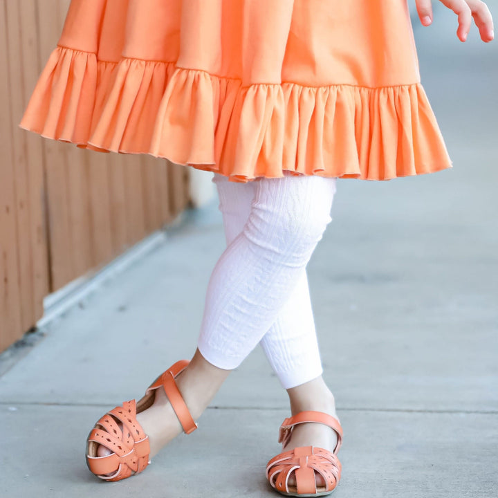 little girl in orange twirl dress and white footless tights